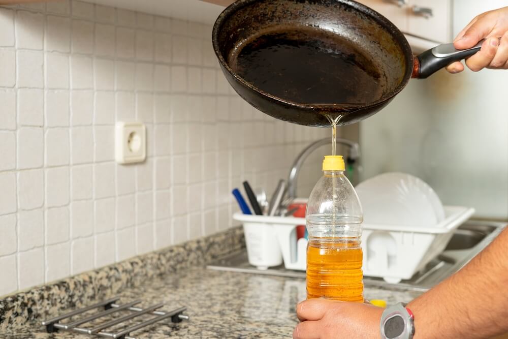 キッチンでフライパンの油をペットボトルに移す作業