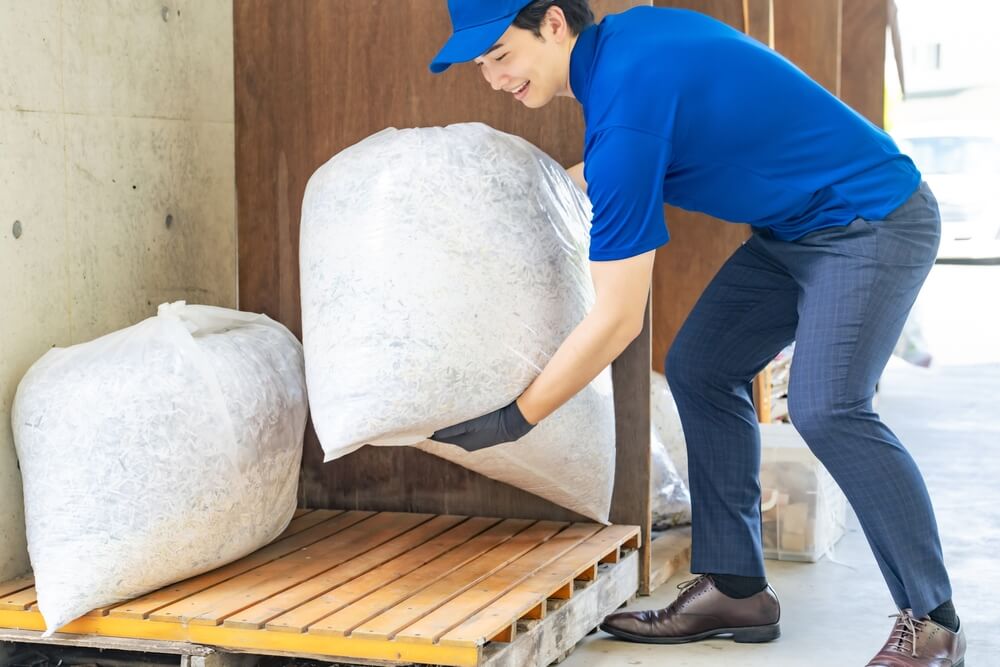 青い作業服の男性が家具を運搬する作業